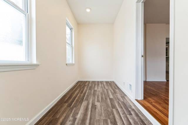 interior space featuring dark wood-type flooring, a wealth of natural light, visible vents, and baseboards