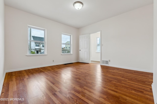 spare room with baseboards, visible vents, and wood finished floors