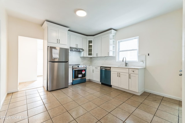 kitchen featuring tasteful backsplash, light countertops, appliances with stainless steel finishes, a sink, and under cabinet range hood