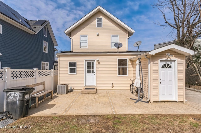 rear view of house featuring central AC unit, fence, and a patio