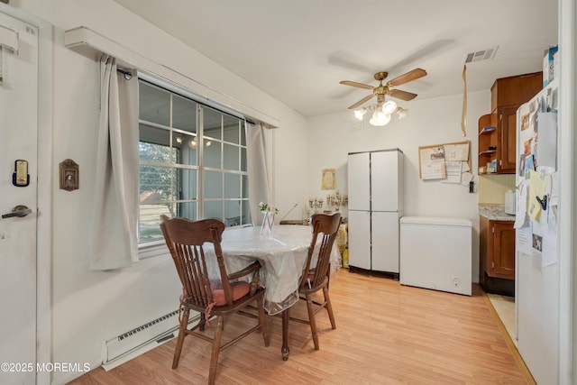 dining space with ceiling fan, baseboard heating, light wood-type flooring, and visible vents