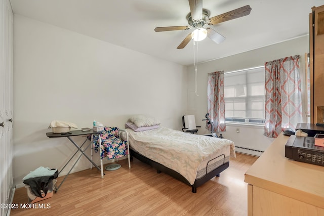 bedroom featuring a baseboard heating unit, light wood-style flooring, and a ceiling fan