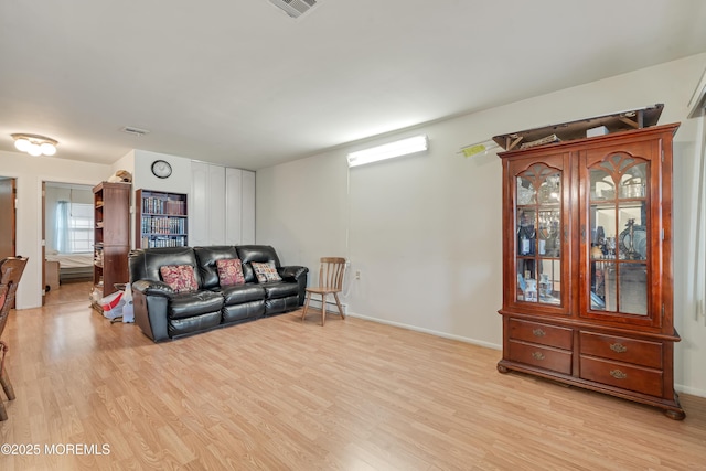 living room featuring light wood-style floors, visible vents, and baseboards