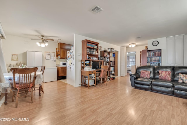 living room featuring a ceiling fan, visible vents, and light wood-style flooring