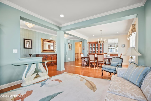 living area with a chandelier, baseboards, wood finished floors, and crown molding