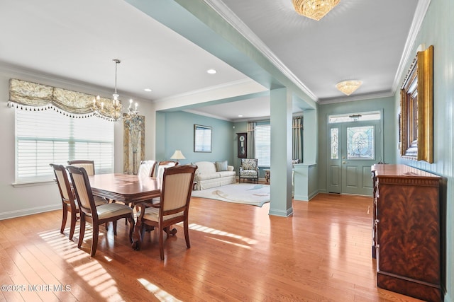 dining area with a notable chandelier, baseboards, crown molding, and light wood-style floors