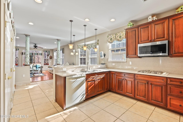 kitchen with light countertops, a peninsula, light tile patterned flooring, white appliances, and a sink