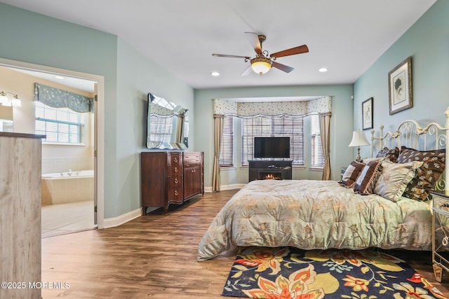 bedroom featuring a ceiling fan, wood finished floors, baseboards, ensuite bath, and recessed lighting