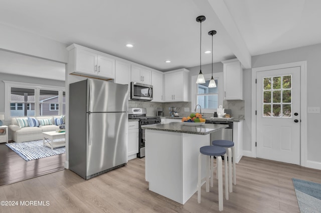 kitchen with appliances with stainless steel finishes, white cabinetry, light wood finished floors, and tasteful backsplash