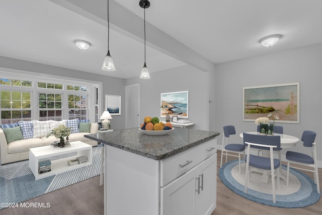 kitchen featuring light wood finished floors, pendant lighting, white cabinets, and a center island