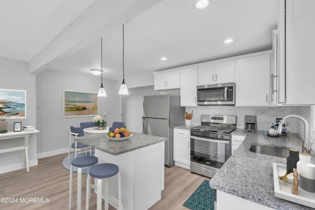 kitchen featuring appliances with stainless steel finishes, a sink, white cabinetry, and tasteful backsplash