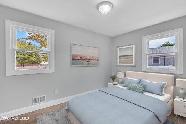 bedroom featuring baseboards, visible vents, and wood finished floors