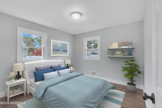 bedroom with wood finished floors, visible vents, and baseboards