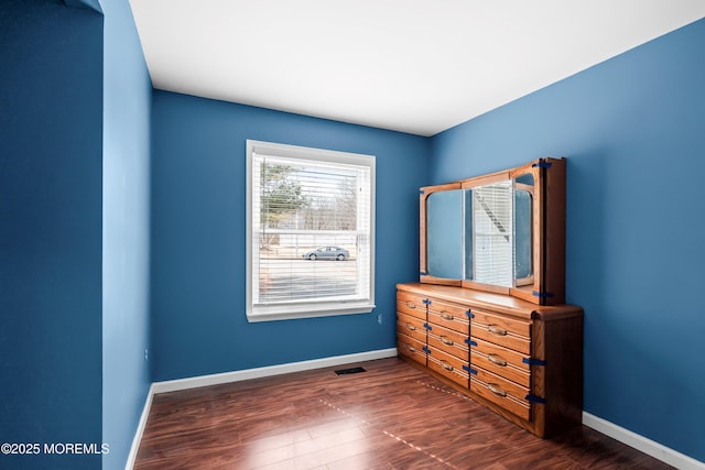 unfurnished bedroom with dark wood finished floors, visible vents, and baseboards