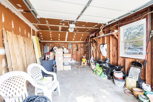 garage featuring wood walls, electric panel, and a garage door opener