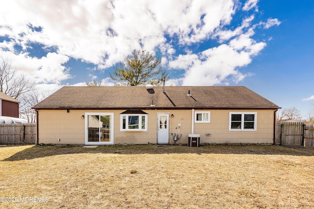 back of house featuring roof with shingles, cooling unit, a fenced backyard, and a lawn