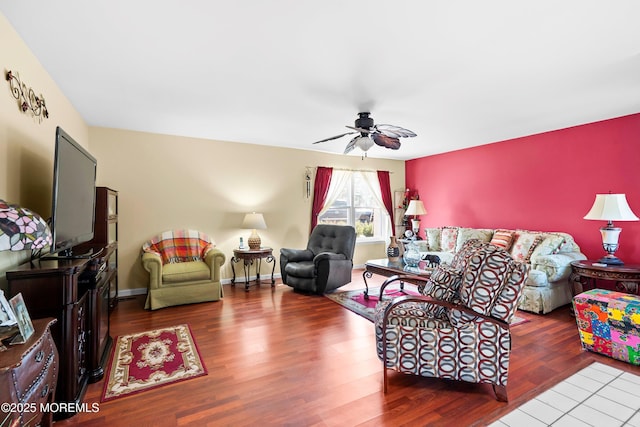 living area featuring baseboards, a ceiling fan, and wood finished floors