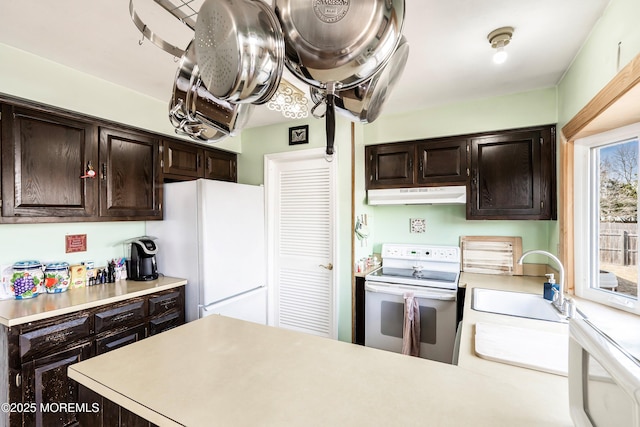 kitchen with light countertops, white appliances, a sink, and under cabinet range hood