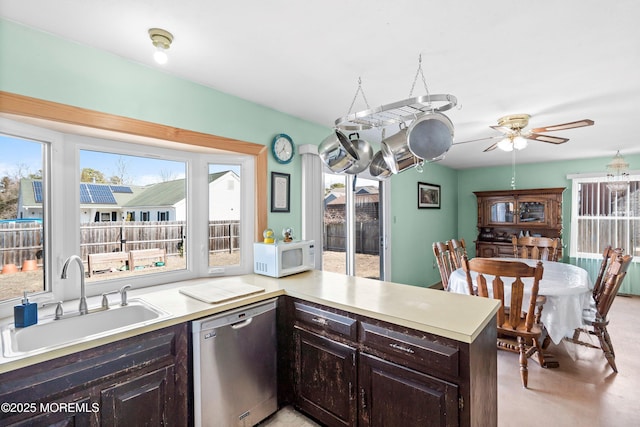 kitchen with dishwasher, white microwave, light countertops, dark brown cabinets, and a sink