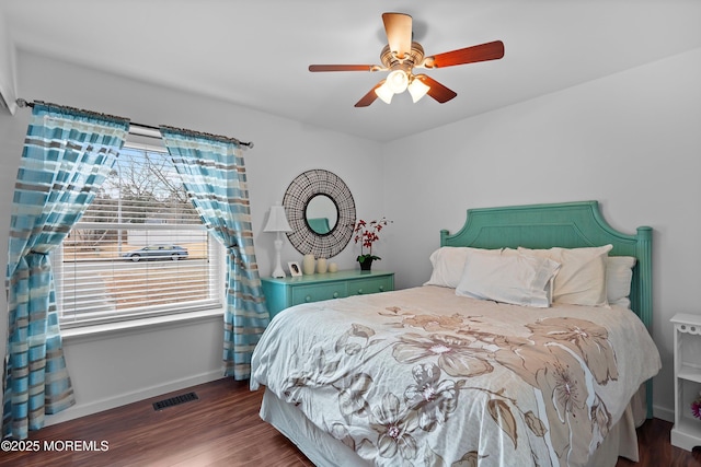 bedroom with a ceiling fan, baseboards, visible vents, and wood finished floors