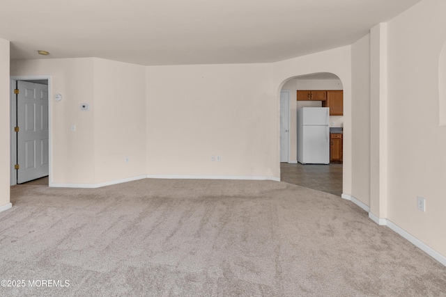 carpeted empty room with arched walkways and baseboards