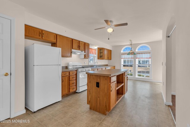 kitchen featuring a kitchen island, under cabinet range hood, light countertops, white appliances, and a sink