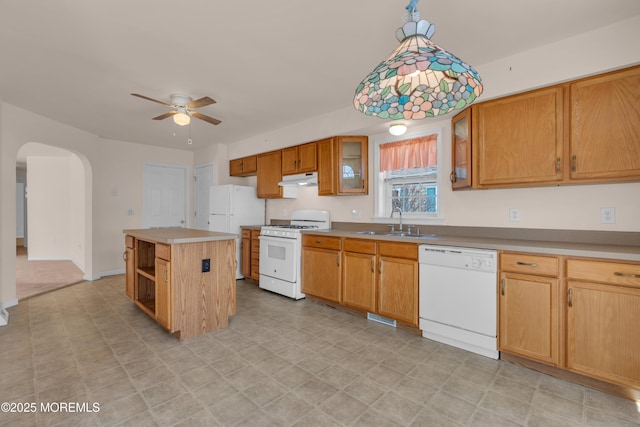 kitchen with a kitchen island, under cabinet range hood, arched walkways, white appliances, and a sink