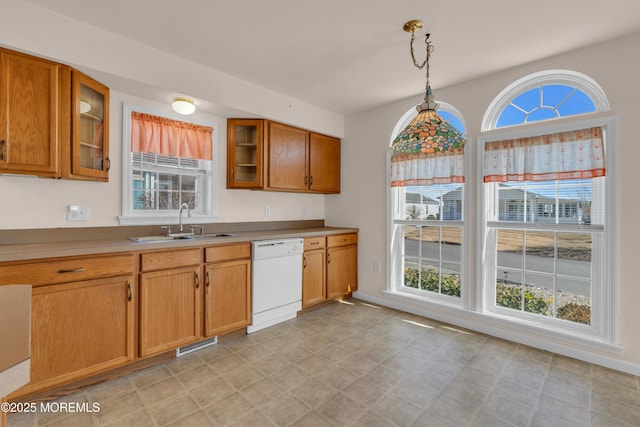 kitchen featuring brown cabinetry, visible vents, a sink, glass insert cabinets, and dishwasher