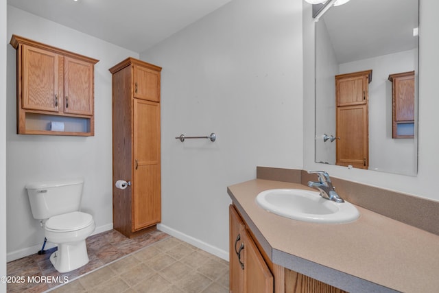 bathroom with toilet, vanity, and baseboards