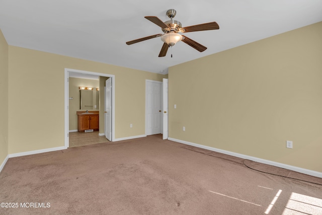 unfurnished bedroom with ensuite bath, carpet flooring, baseboards, and ceiling fan