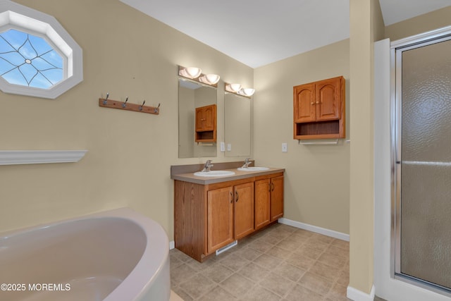 bathroom with a bath, double vanity, baseboards, and a sink