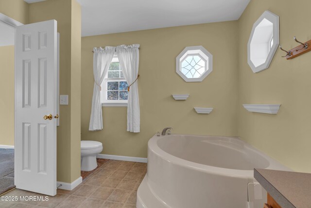 full bathroom with tile patterned flooring, baseboards, toilet, a garden tub, and vanity