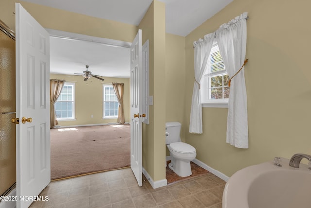 bathroom with toilet, a healthy amount of sunlight, baseboards, and ceiling fan