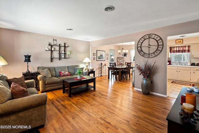 living room featuring light wood finished floors, visible vents, and baseboards