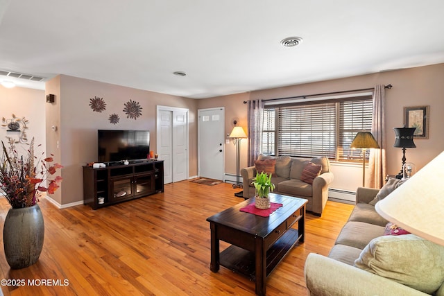 living area featuring a baseboard heating unit, wood finished floors, and visible vents