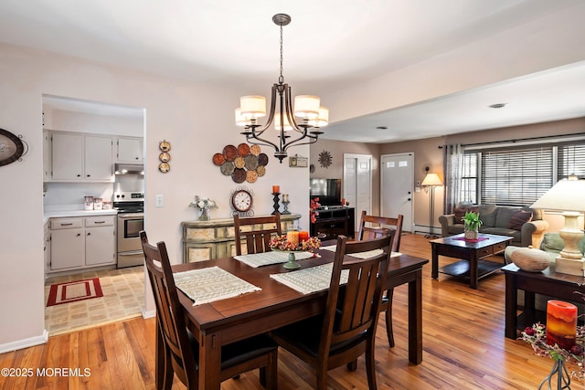 dining room featuring a baseboard radiator, visible vents, light wood-style flooring, a chandelier, and baseboards