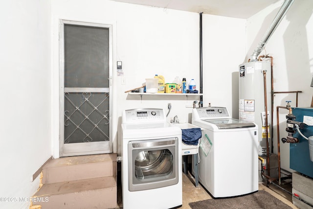 washroom with laundry area, a heating unit, gas water heater, washing machine and dryer, and a sink