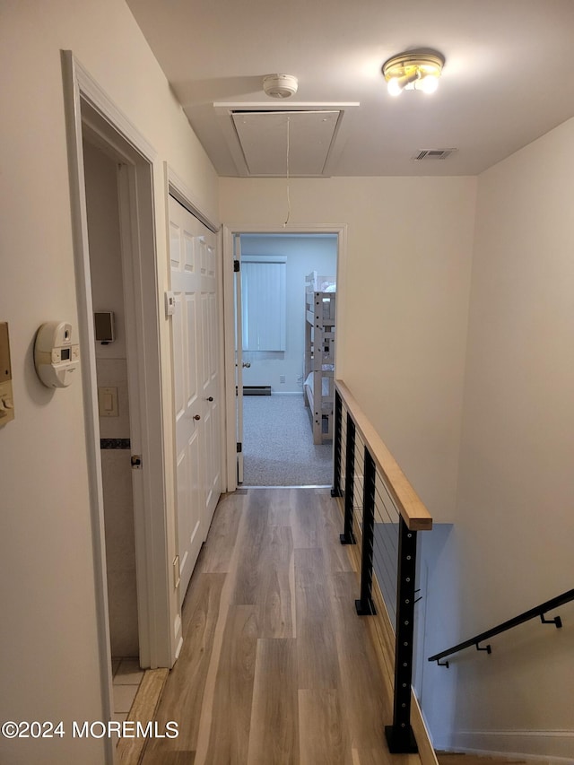 hallway with visible vents, wood finished floors, and attic access