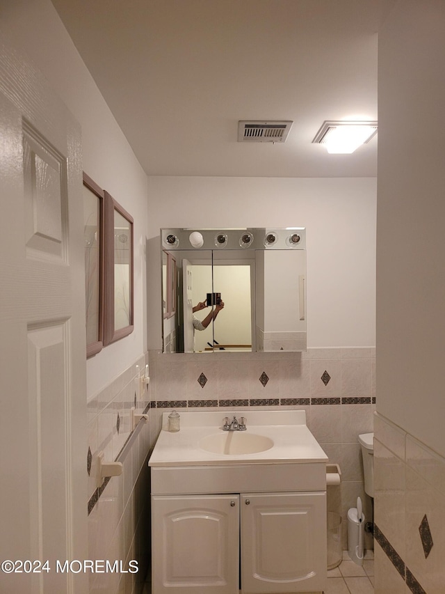 bathroom with toilet, visible vents, tile walls, and vanity