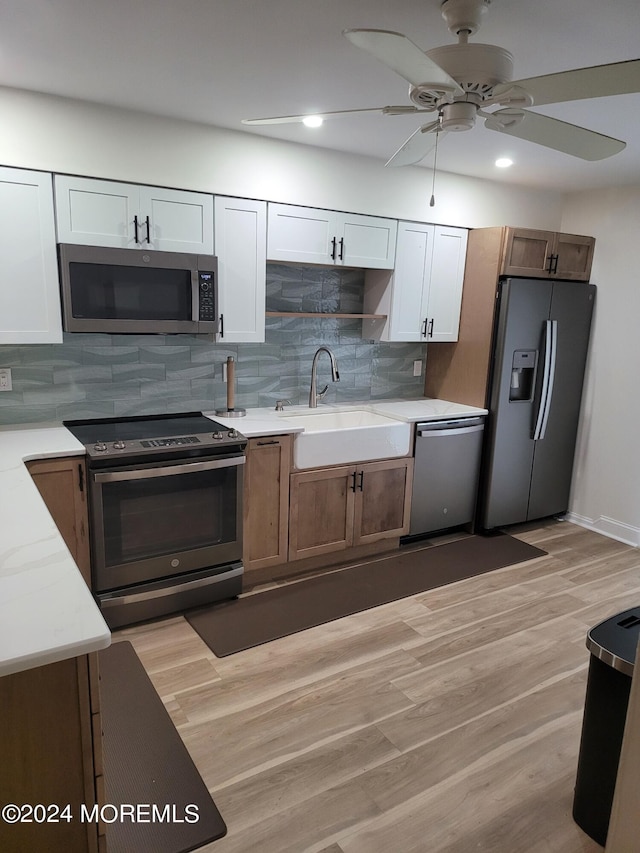 kitchen with appliances with stainless steel finishes, light wood-type flooring, a sink, and decorative backsplash