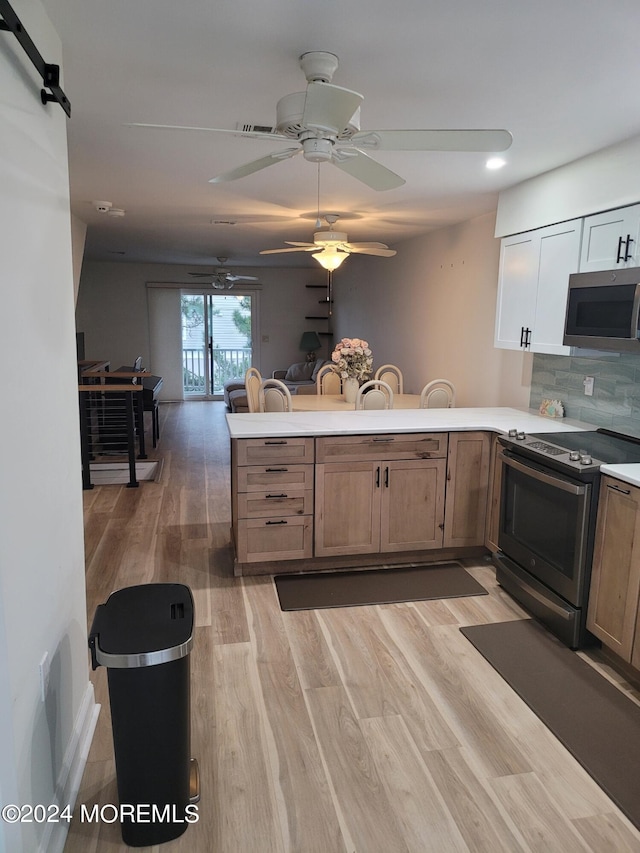 kitchen featuring decorative backsplash, a peninsula, stainless steel appliances, light countertops, and light wood-type flooring