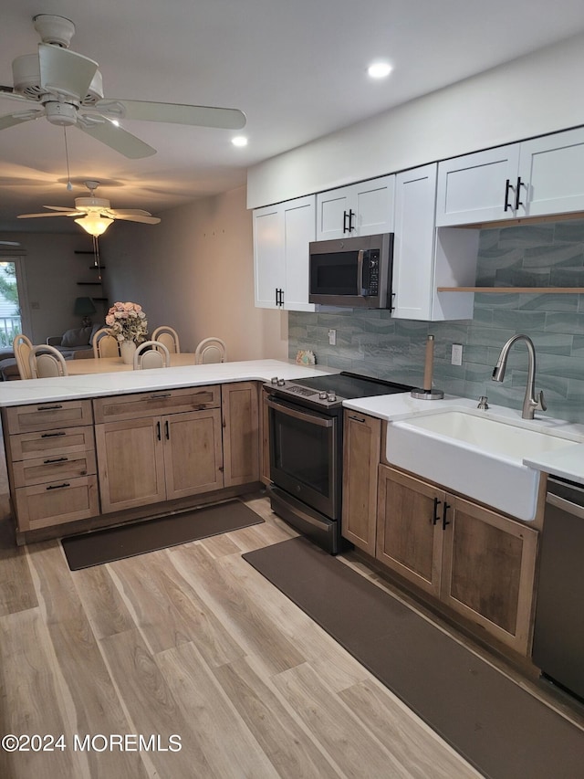 kitchen featuring light countertops, appliances with stainless steel finishes, light wood-style floors, a sink, and a peninsula