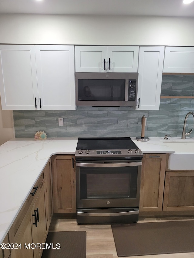 kitchen featuring white cabinetry, decorative backsplash, stainless steel appliances, and a sink