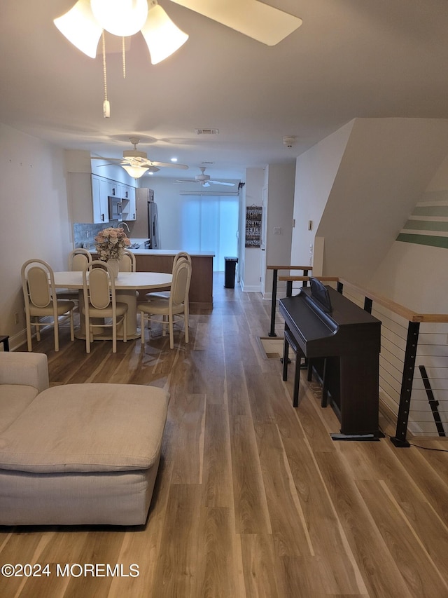 living room with a ceiling fan, baseboards, visible vents, and wood finished floors