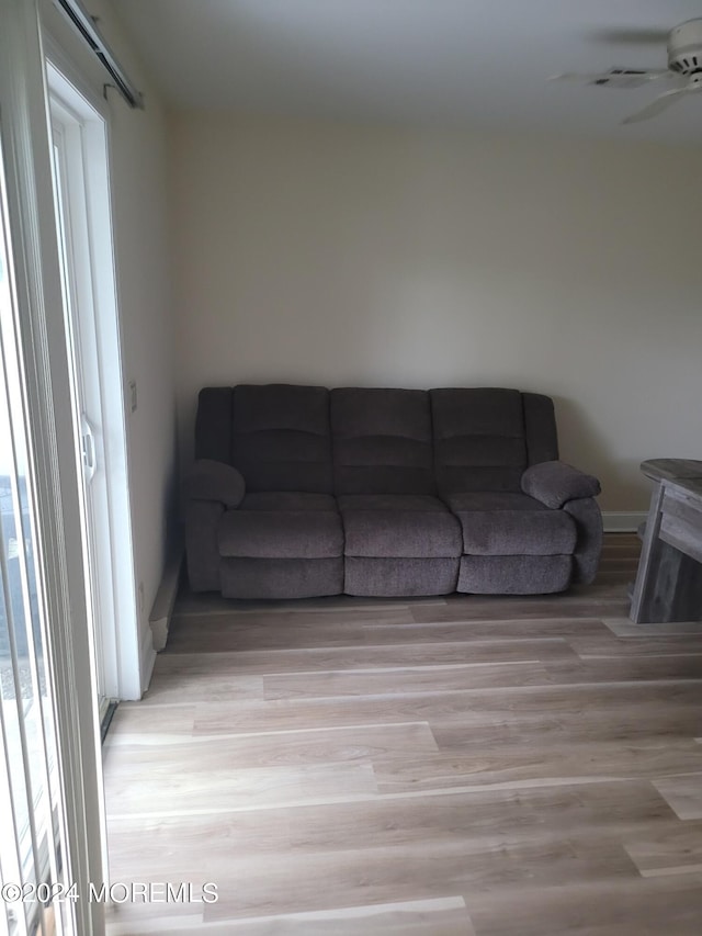 living area featuring ceiling fan, baseboards, and wood finished floors