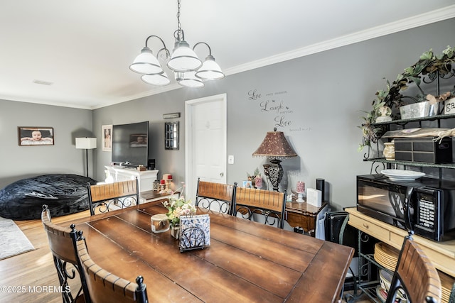 dining area with an inviting chandelier, wood finished floors, visible vents, and crown molding