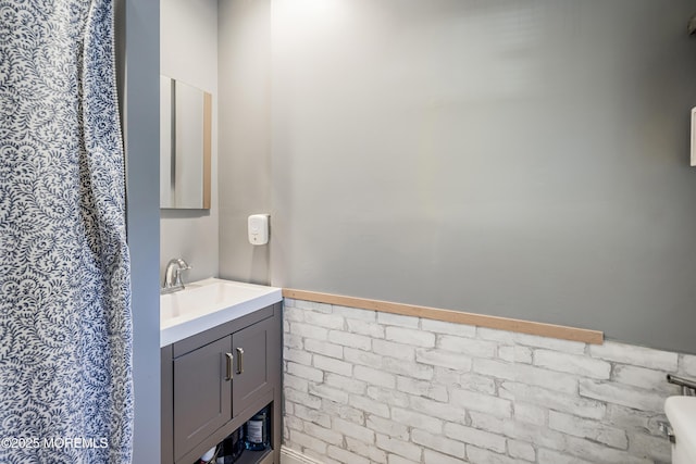 bathroom featuring vanity and brick wall