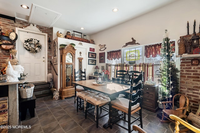 dining space with recessed lighting, stone finish floor, and brick wall