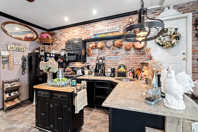 kitchen with ornamental molding, a sink, brick wall, dark cabinetry, and black appliances