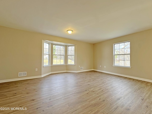 empty room with baseboards, visible vents, and wood finished floors